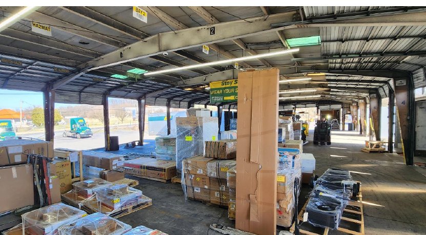 Inside the cross-dock: palletized freight staged along the dock with open doors to the yard