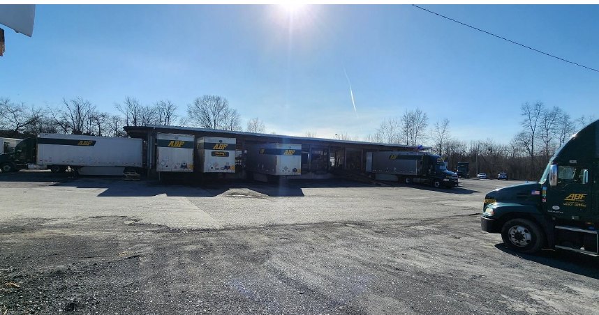 The terminal building and its dock line on a clear day, trailers backed to the doors